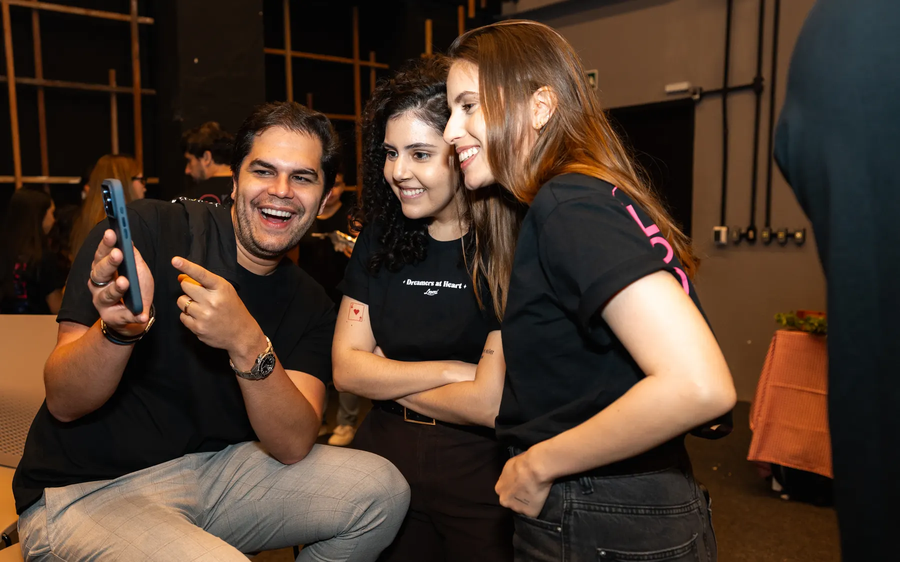 Três Loomers rindo juntos olhando um celular